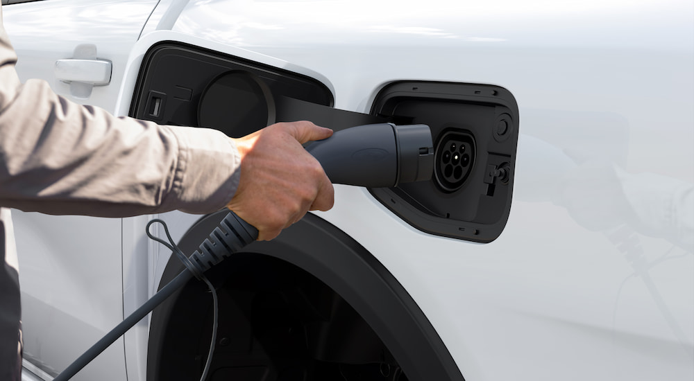 A close-up of a white 2025 Ford Ranger PHEV being charged.