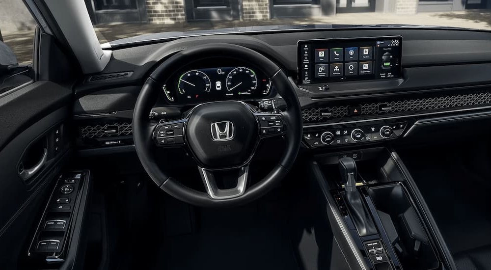 The steering wheel and dashboard in the black interior of a 2024 Honda Accord Touring.