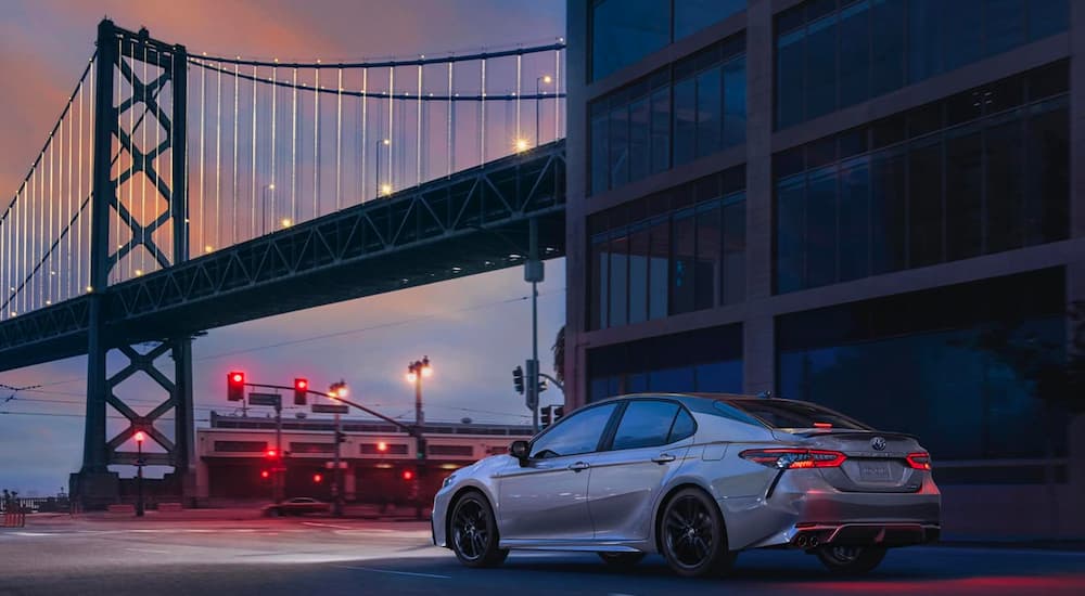 A silver 2019 Toyota Camry is shown parked near used cars for sale.