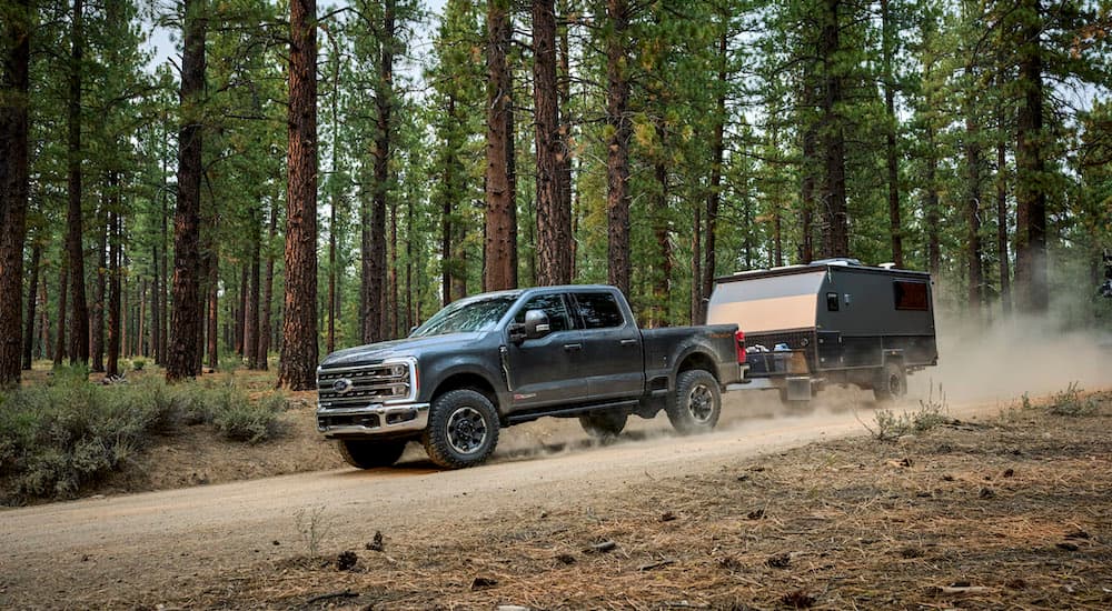 A grey 2024 Ford F-250 Tremor is shown from the side while towing a trailer.