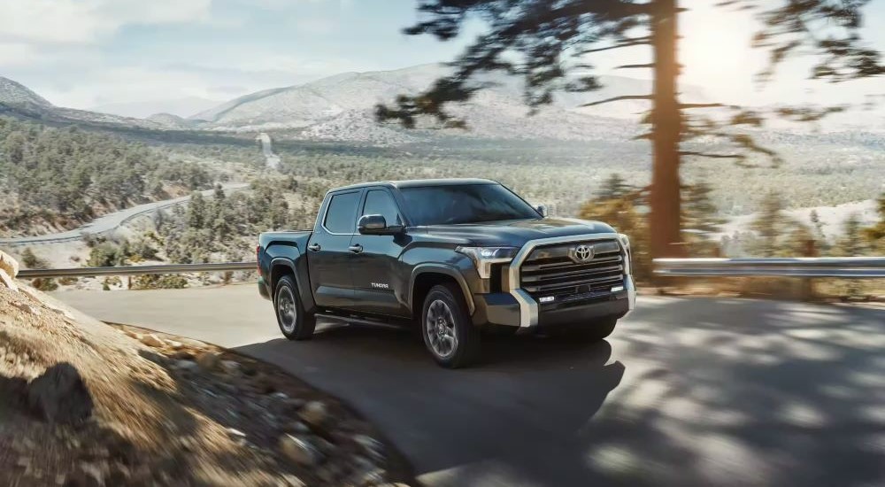 A black 2024 Toyota Tundra Limited angled right and driving from a Toyota dealer.