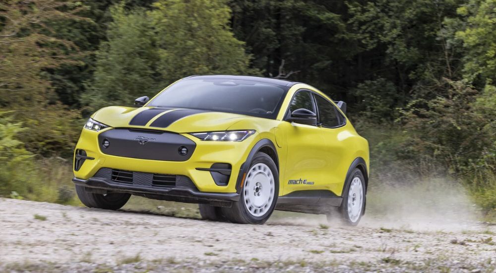 A yellow and black 2024 Ford Mustang Mach-E Rally Editing driving off-road.