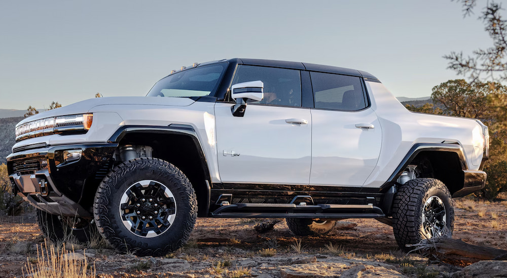 Side view of a white 2024 GMC Hummer EV Pickup parked on a mountaintop.