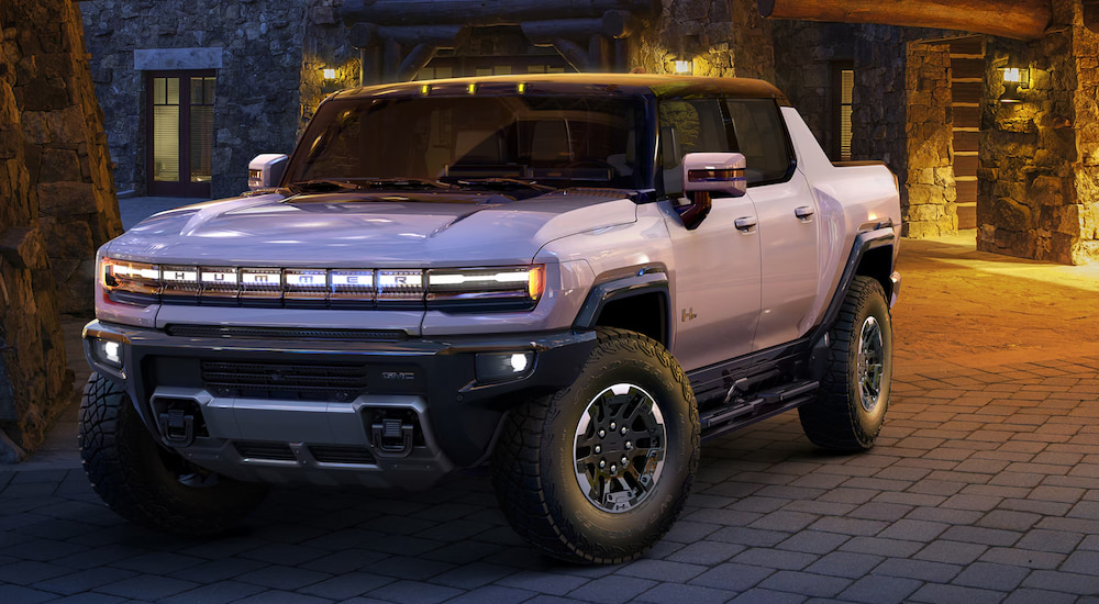 A white 2024 GMC Hummer EV Pickup parked in a cobblestone courtyard at night.