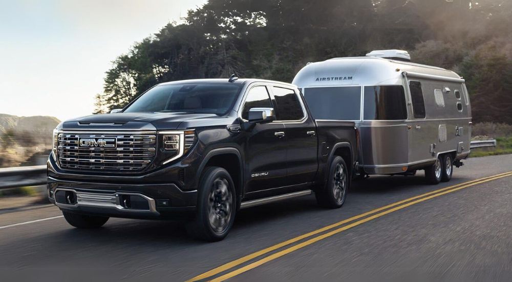 A black 2024 GMC Sierra 1500 Denali towing an airstream camper.