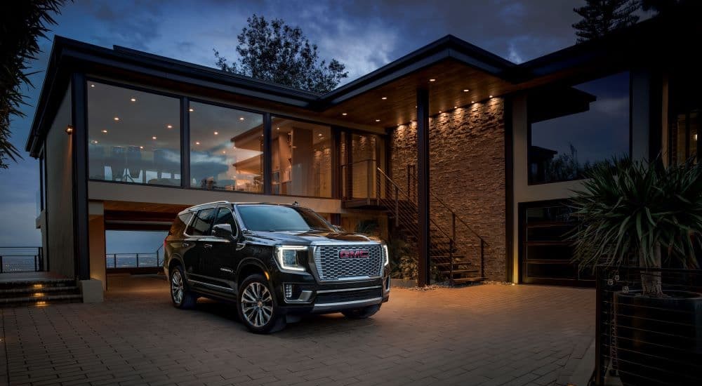 A black 2024 GMC Yukon Denali parked on a driveway.