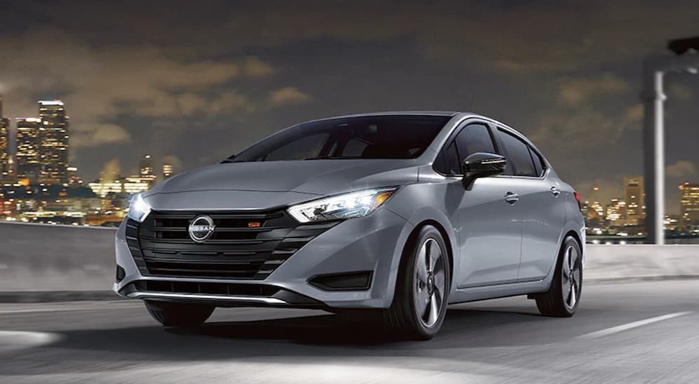 A silver 2024 Nissan Versa SR is shown driving on a highway to view a Nissan Versa for sale.