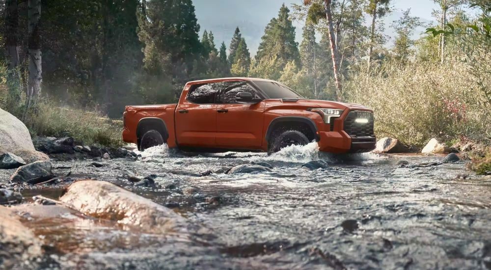 A red 2024 Toyota Tundra TRD Pro driving over a shallow river.