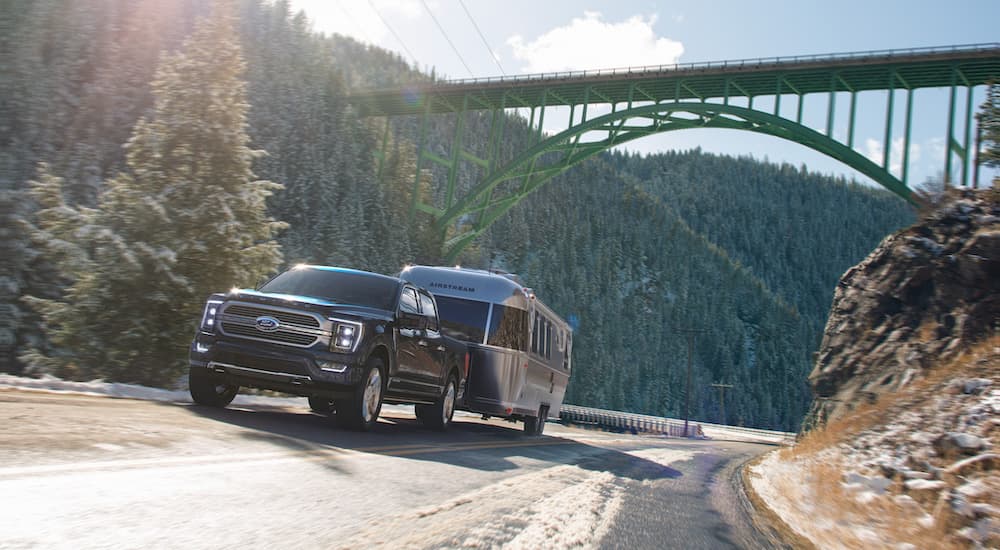 A black 2024 Ford F-150 Limited is shown towing an Airstream camper.