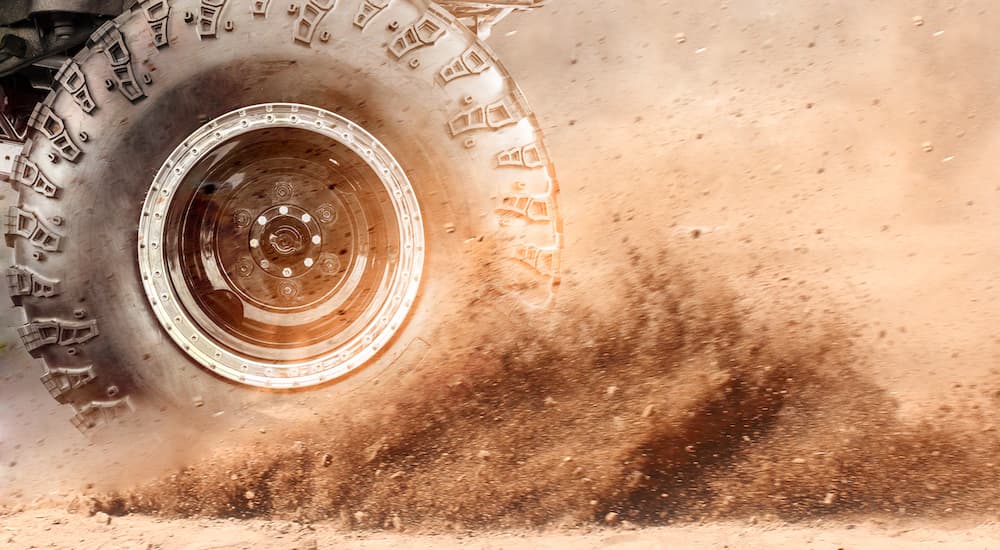 An off-road tire is shown kicking up dirt.