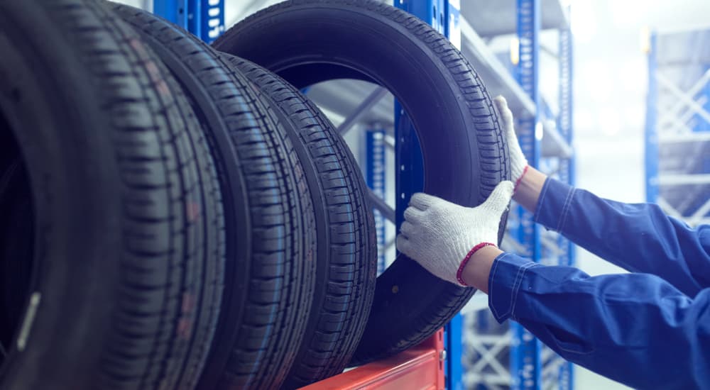 A mechanic is shown selecting a tire off of a rack.