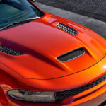 Close-up of the hood of an orange 2023 Dodge Charger SRT Hellcat at a Dodge dealer.