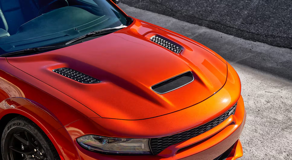 Close-up of the hood of an orange 2023 Dodge Charger SRT Hellcat at a Dodge dealer.