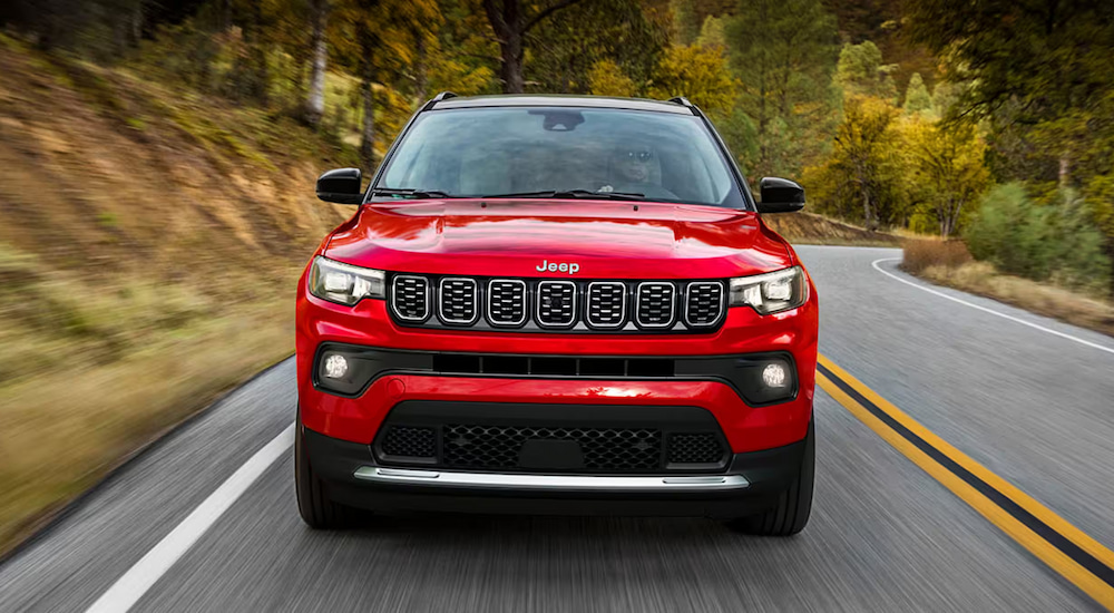 Head-on view of a red 2024 Jeep Compass driving on an open road.