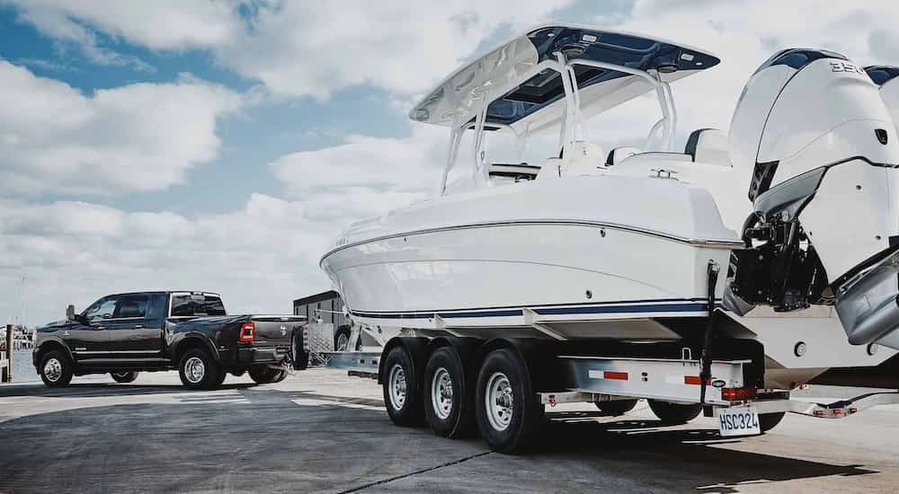 A grey 2024 Ram 3500 is shown from the rear at an angle while towing a boat.