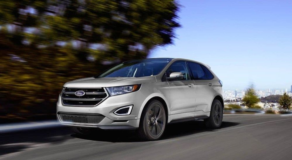 A silver 2018 Ford Edge driving to a used Ford dealer.