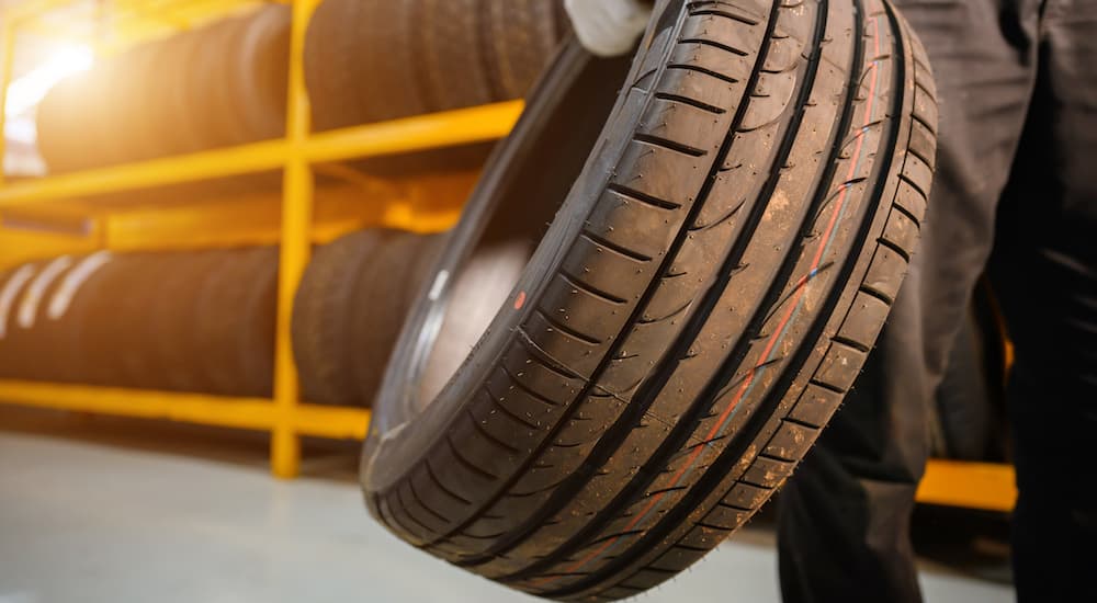 A mechanic is shown holding a tire in a tire shop.