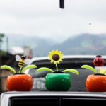 Three faux flower vases sitting on the dashboard of a car.