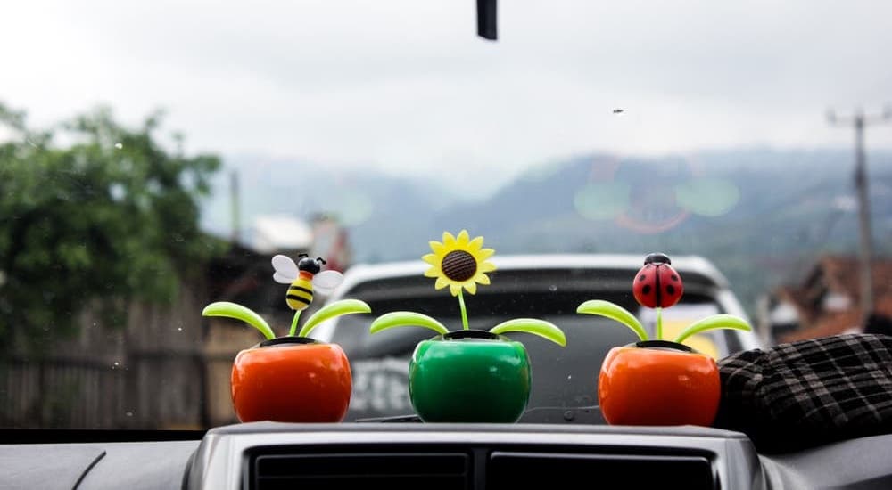 Three faux flower vases sitting on the dashboard of a car.