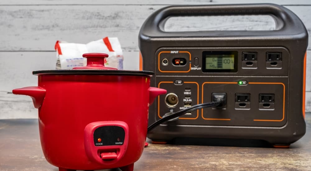 A low-wattage red rice cooker plugged into a generator.