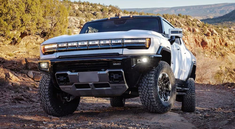 A white 2024 GMC Hummer EV Pickup is shown parked off-road.