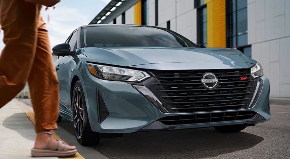 Front angle view of a person walking by a grey 2024 Nissan Sentra SR.