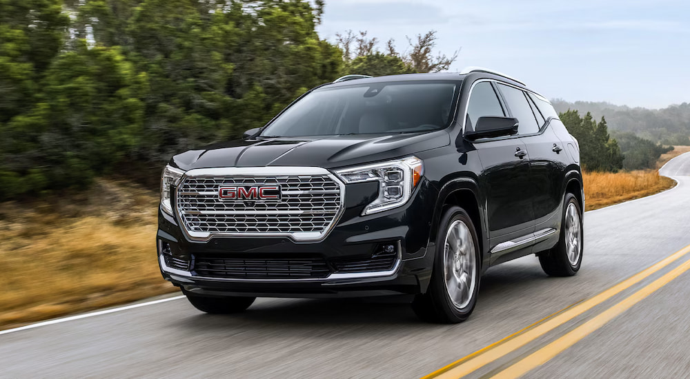 A black 2024 GMC Terrain Denali driving on an open road.