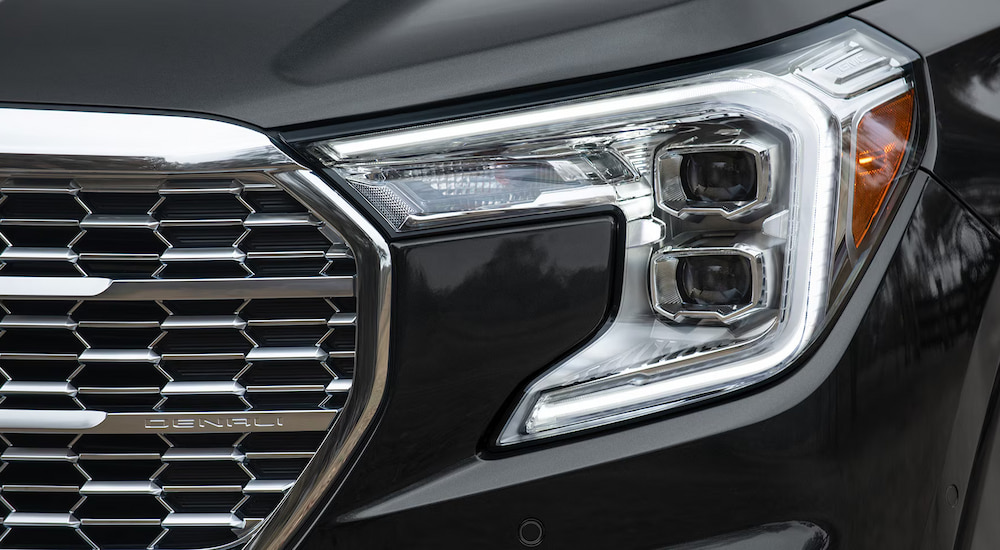 Close-up of the grille and headlight of a black 2024 GMC Terrain Denali.