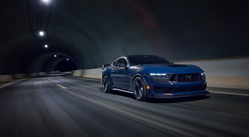 A blue Ford Mustang Dark Horse is shown from the front at an angle.