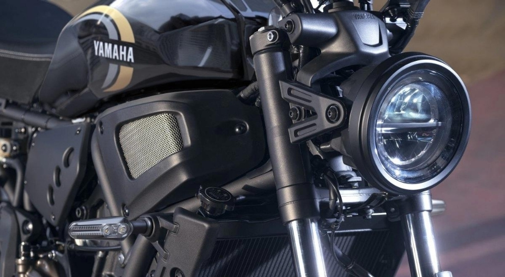 A close-up shows the headlight on a black 2023 Yamaha XSR700.