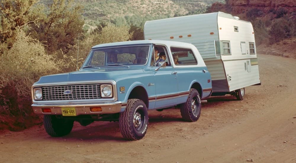 A blue 1969 Chevy K5 Blazer is shown towing a trailer.