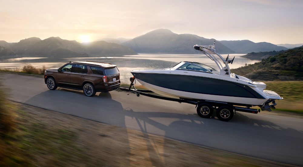 A brown 2021 Chevy Tahoe is shown towing a boat.