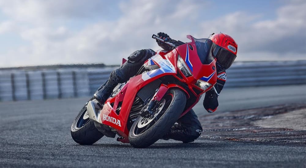 A person is shown leaning into a corner on a 2024 Honda CBR650R.