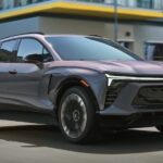 A gray 2025 Chevy Blazer RS EV is shown driving on a city street.