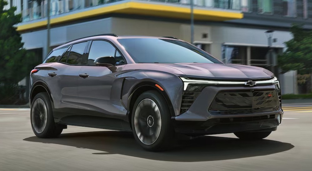 A gray 2025 Chevy Blazer RS EV is shown driving on a city street.