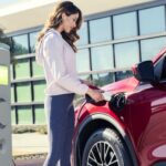 A person is shown charging a red 2025 Ford Escape PHEV.