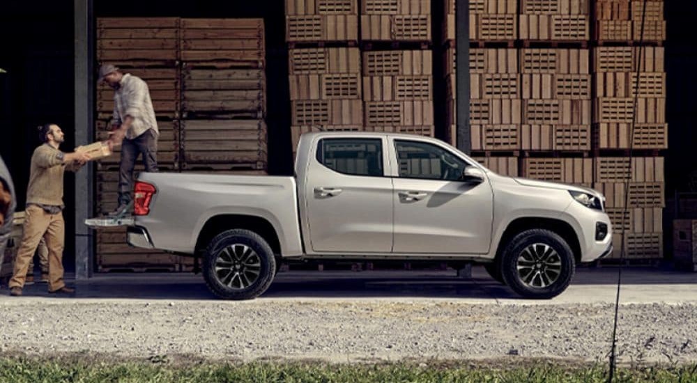 A white 2025 Ram 1200 is shown parked near two workers.