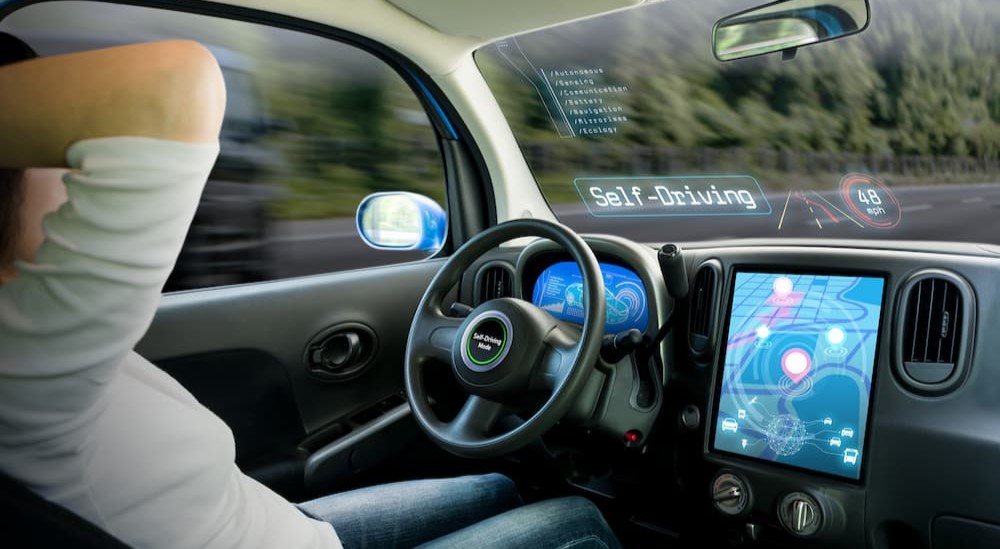 A person is shown sitting in a self-driving car.