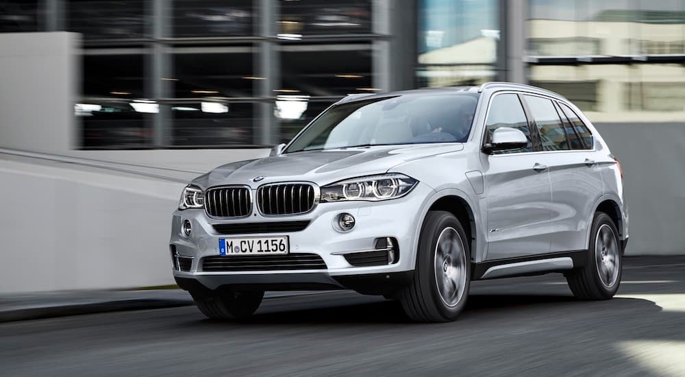 A silver 2015 BMW X5 for sale is shown driving on a city street.