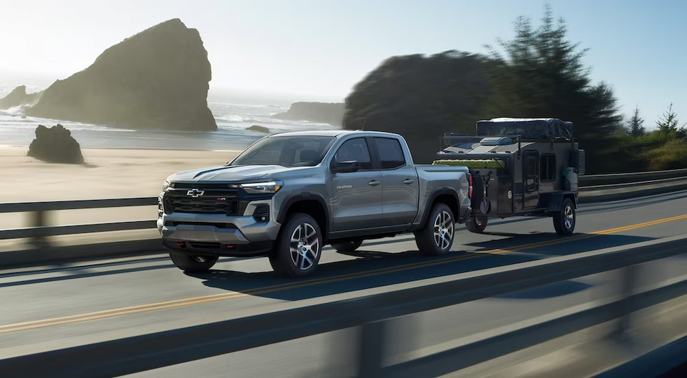 A silver 2024 Chevy Colorado Z71 is shown towing a trailer on a highway.