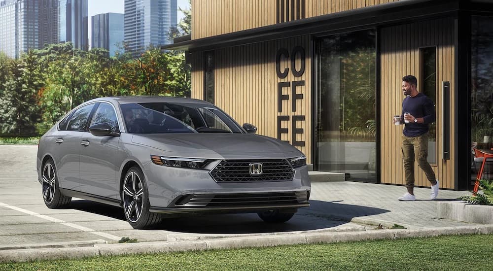 A gray 2025 Honda Accord Sport Hybrid is shown parked near a coffee shop.