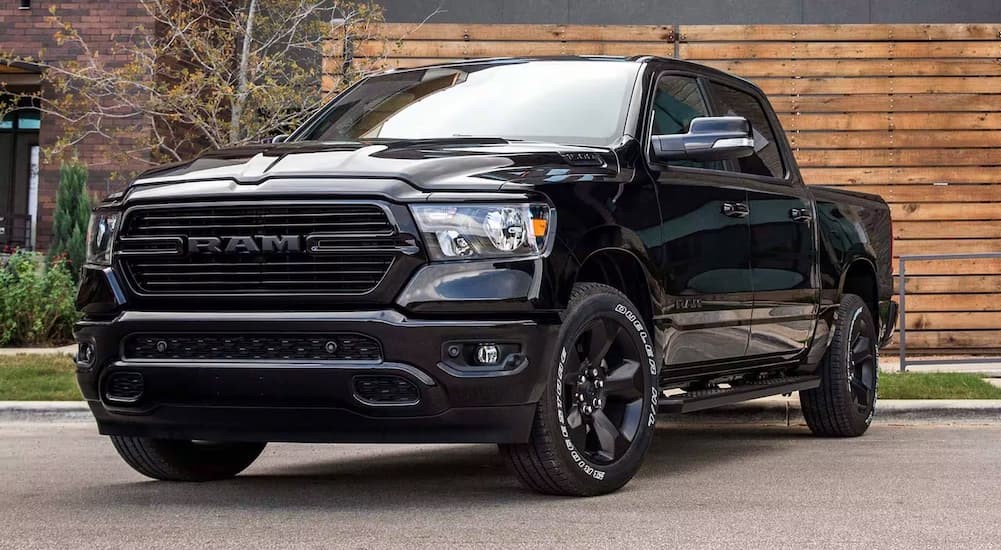 A black 2024 Ram 1500 DT is shown parked near a wooden building.