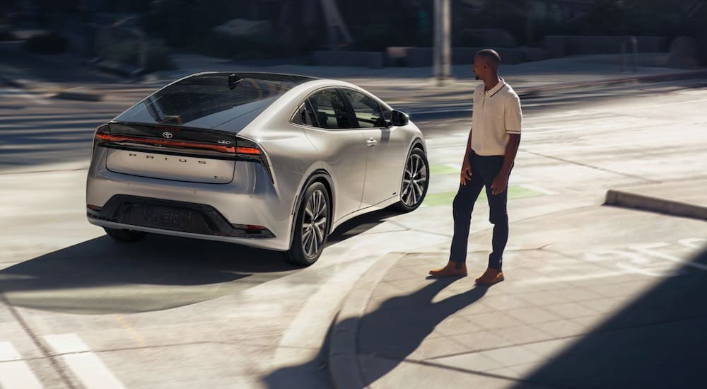 A silver 2024 Toyota Prius is shown driving on a city street.