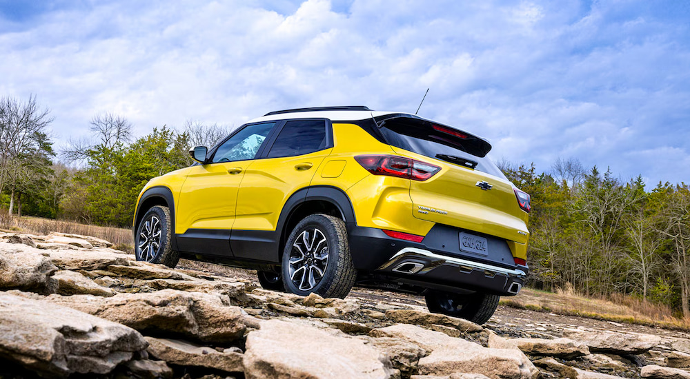 Rear view of a yellow 2025 Chevy Trailblazer off-roading up a rocky hill.