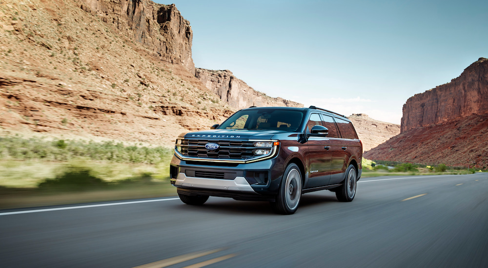 A black 2025 Ford Expedition Platinum Ultimate driving past mesas on the highway.