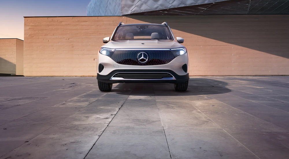 Front angle view of a white 2024 Mercedes-Benz EQB 250 parked by a building.