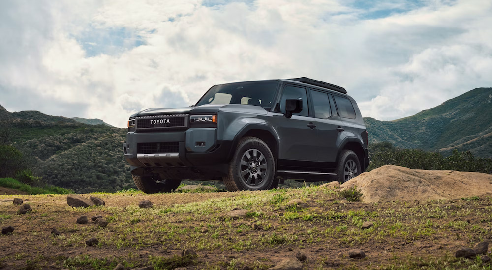 A grey 2024 Toyota Land Cruiser parked off-road on a grassy hill.