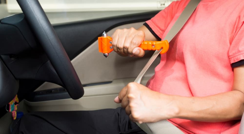 A person is shown holding an emergency car escape tool.