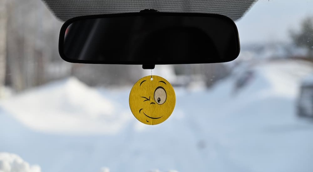 An air freshener is shown hanging from a mirror.