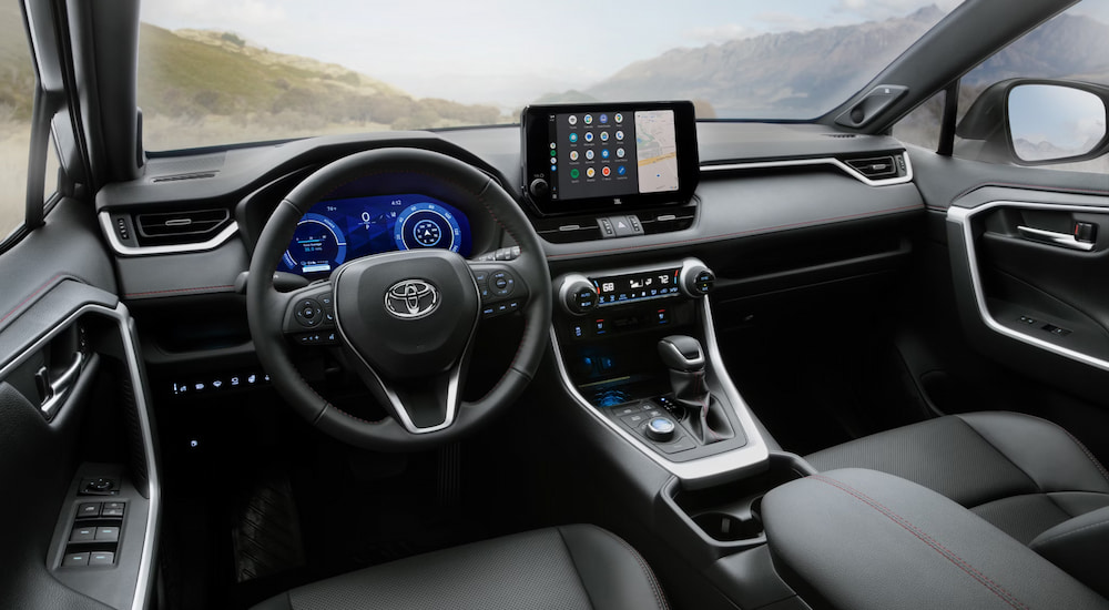 The black interior cabin of a 2025 Toyota RAV4 PHEV as seen from the driver's seat.